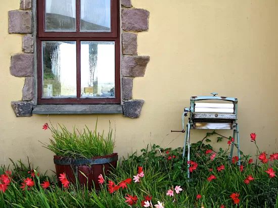 Old clothes wringer machine sitting next to stone wall