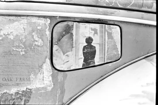 Black and white photo of an old VW gas filler flap decorated with magazine art